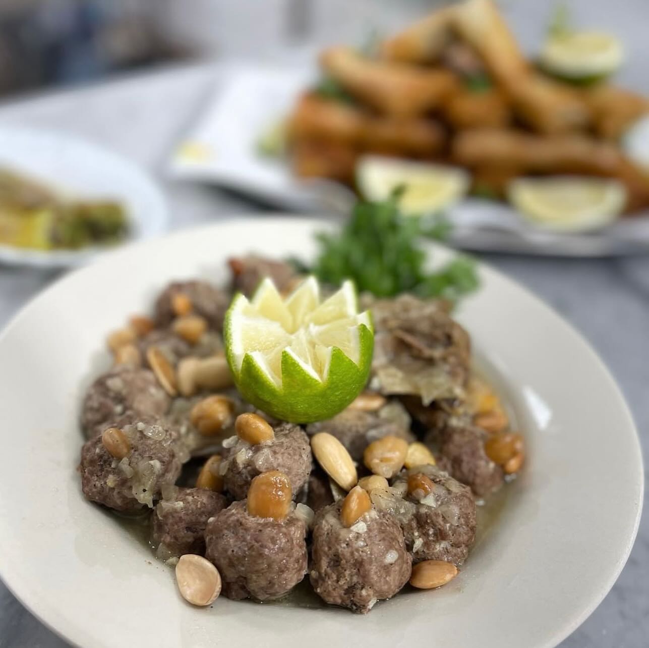 Plat de mtewem aux boulettes de viande, amandes et pois chiches, décoré d'un citron sculpté