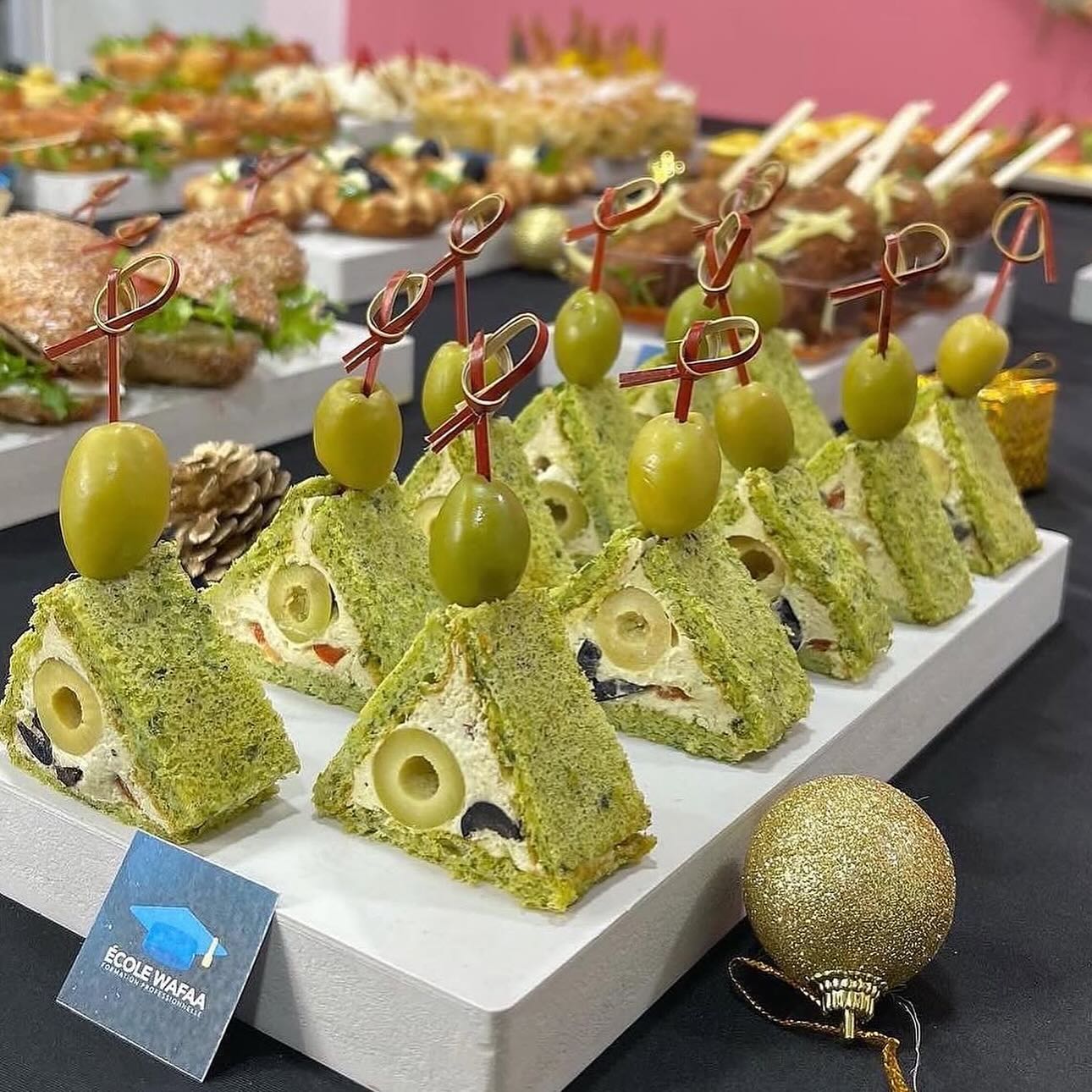 Bouchées salées triangulaires au pain vert, garnies de fromage et olives, piquées de brochettes décoratives