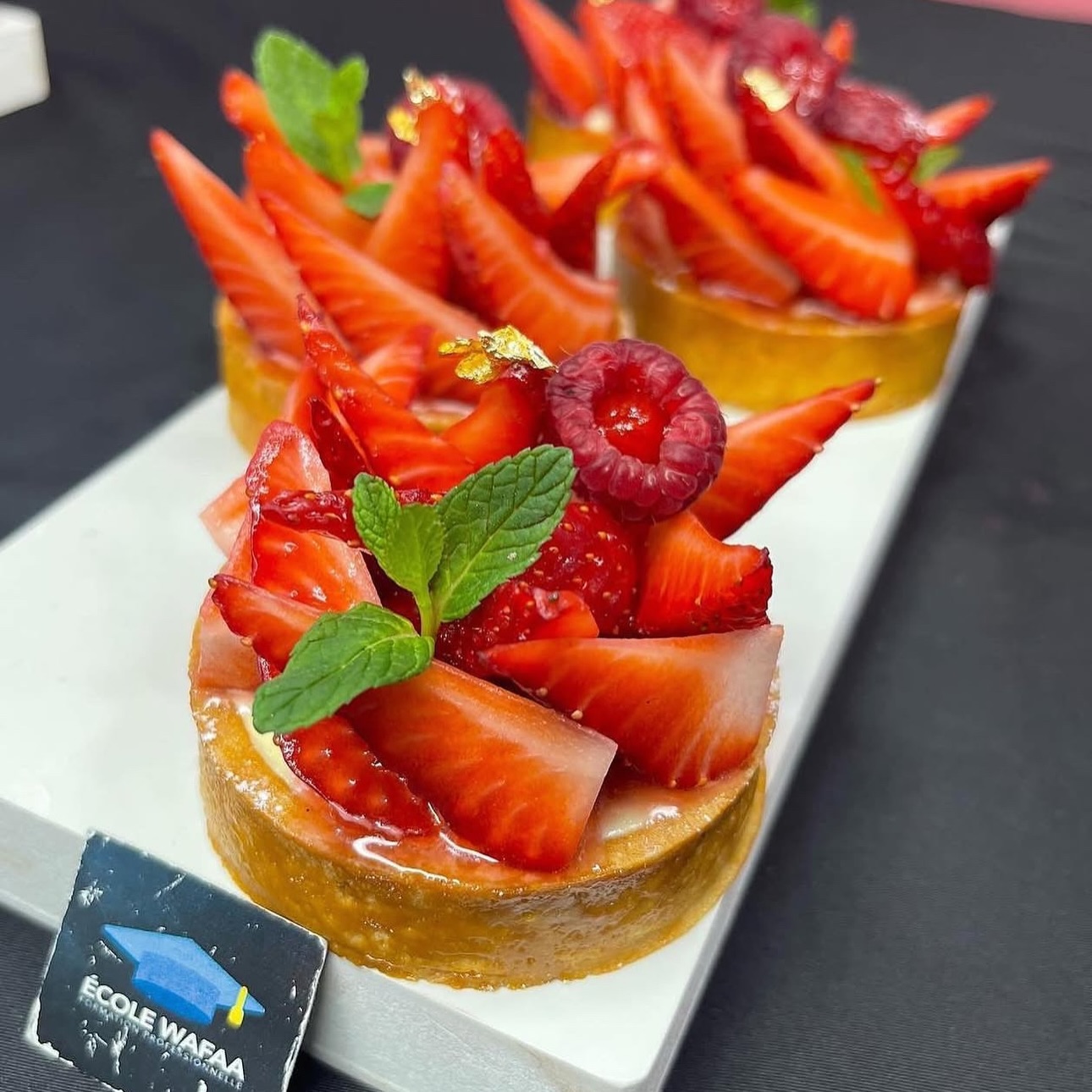 Tartelettes aux fraises fraîches décorées de menthe, framboise et feuille d'or